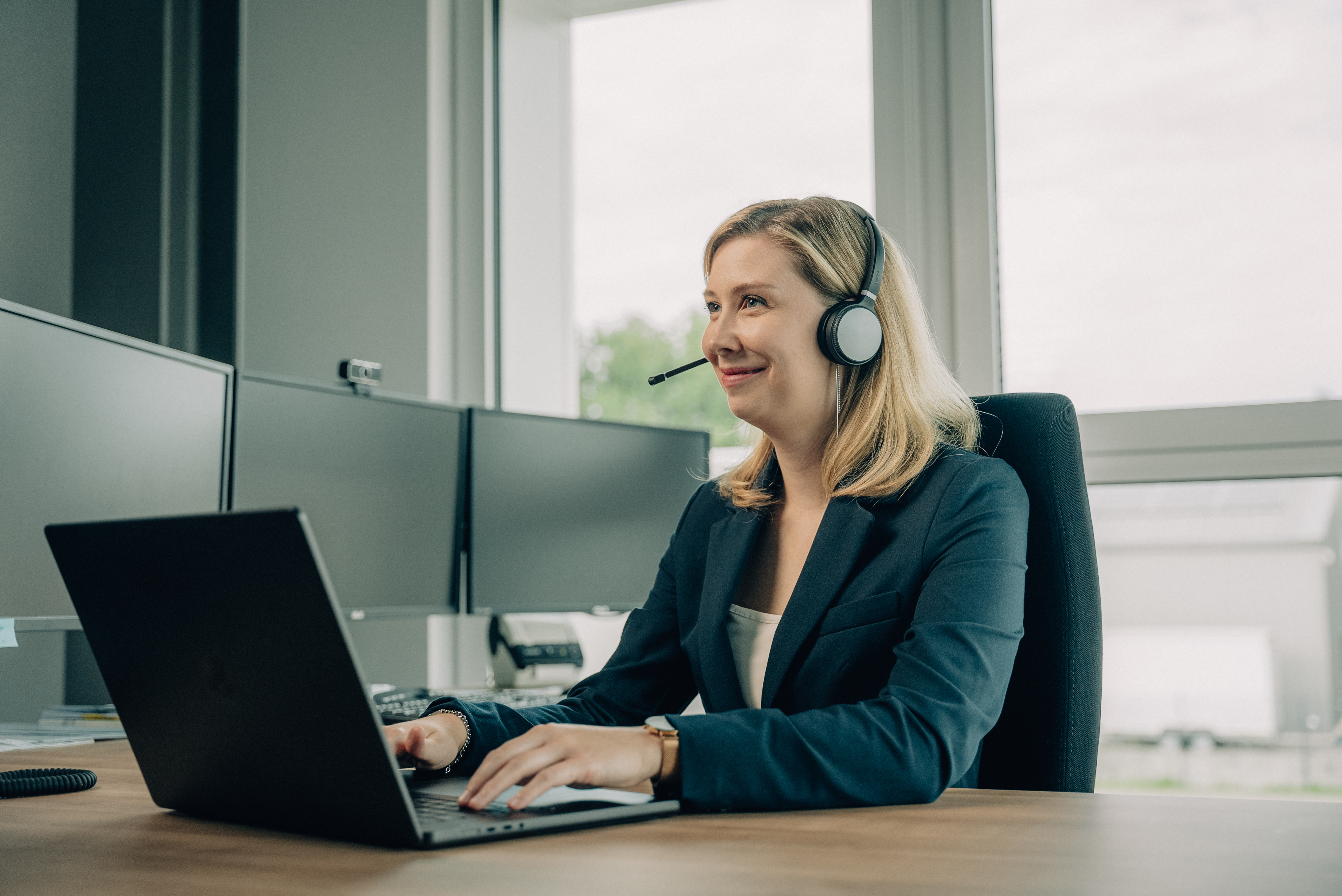 Mitarbeiterin mit Headset am modernen Arbeitsplatz – serviceorientierte Mandantenbetreuung